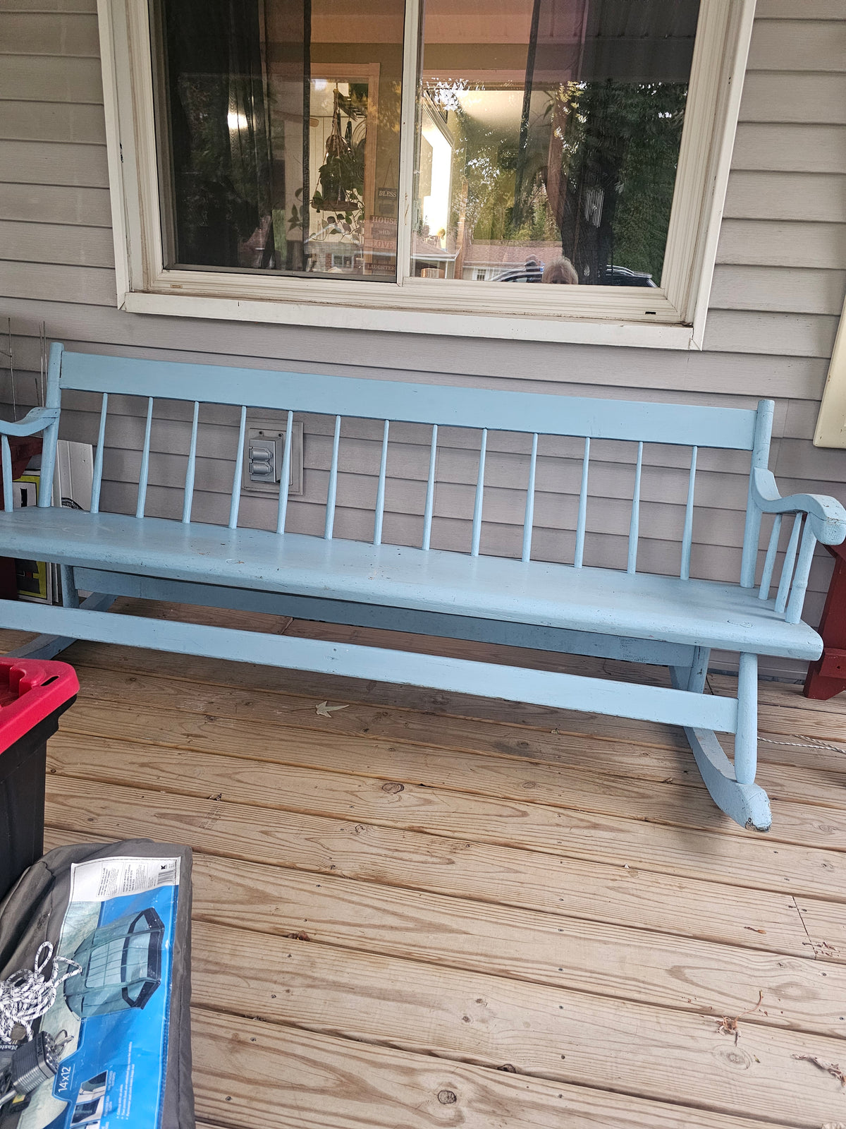 Pale blue painted nanny bench with spindle back, curved arms and visible finish wear